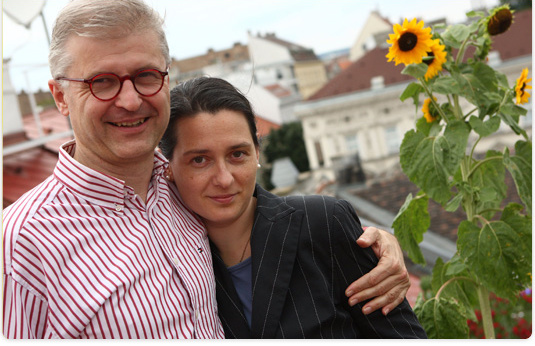 Zwei Menschen mit Sonnenblumen auf einer Dachterrasse in Wien